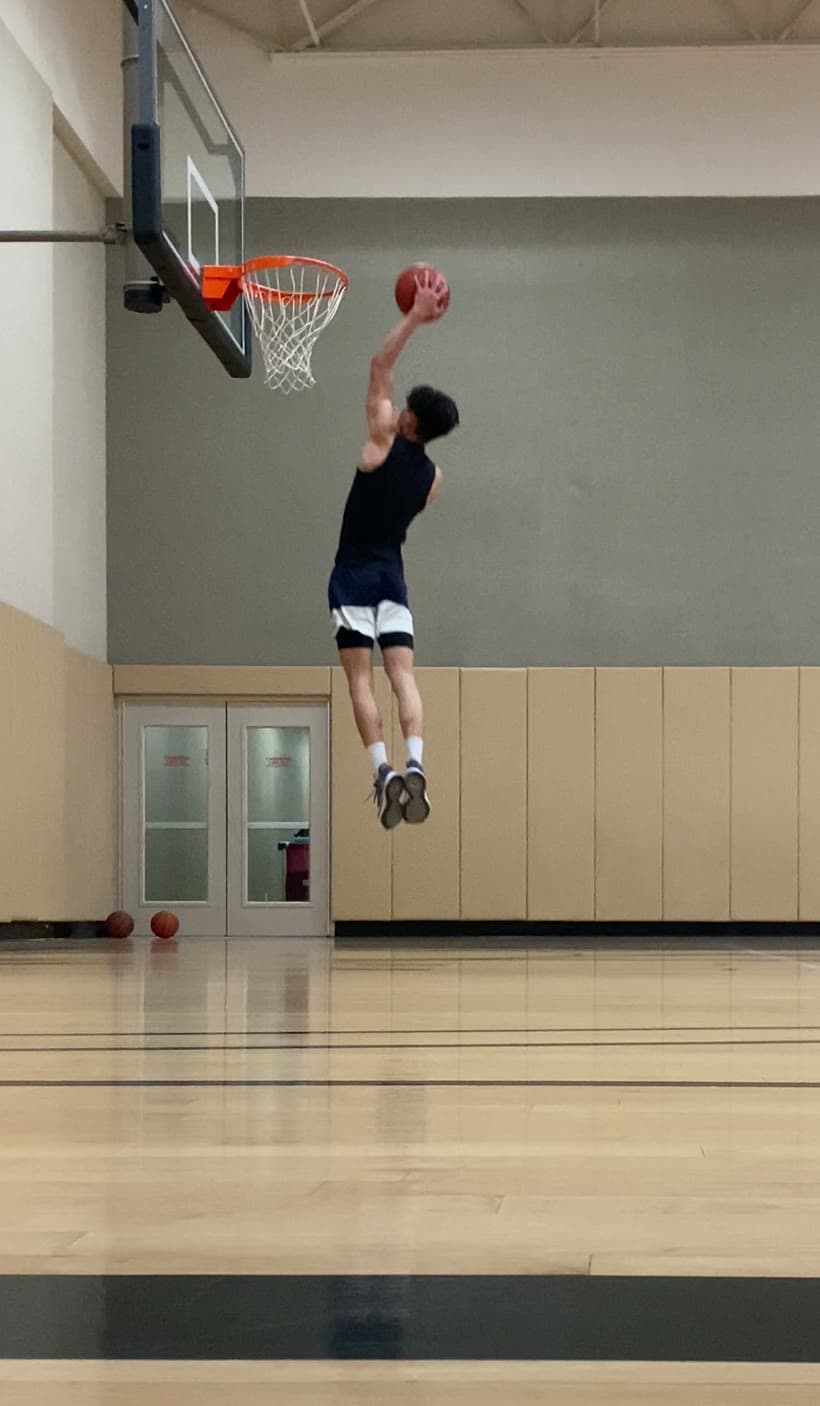 Chris fully airborne above the rim, ball cocked, on his first dunk after surgery